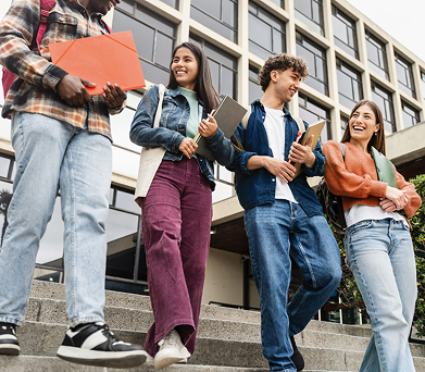 University students walking down campus steps holding folders and notebooks